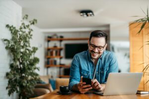 Portrait of a cheerful man using smart phone at home office.